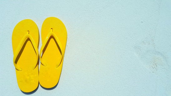 Yellow flip-flops on a pastel torquoise background